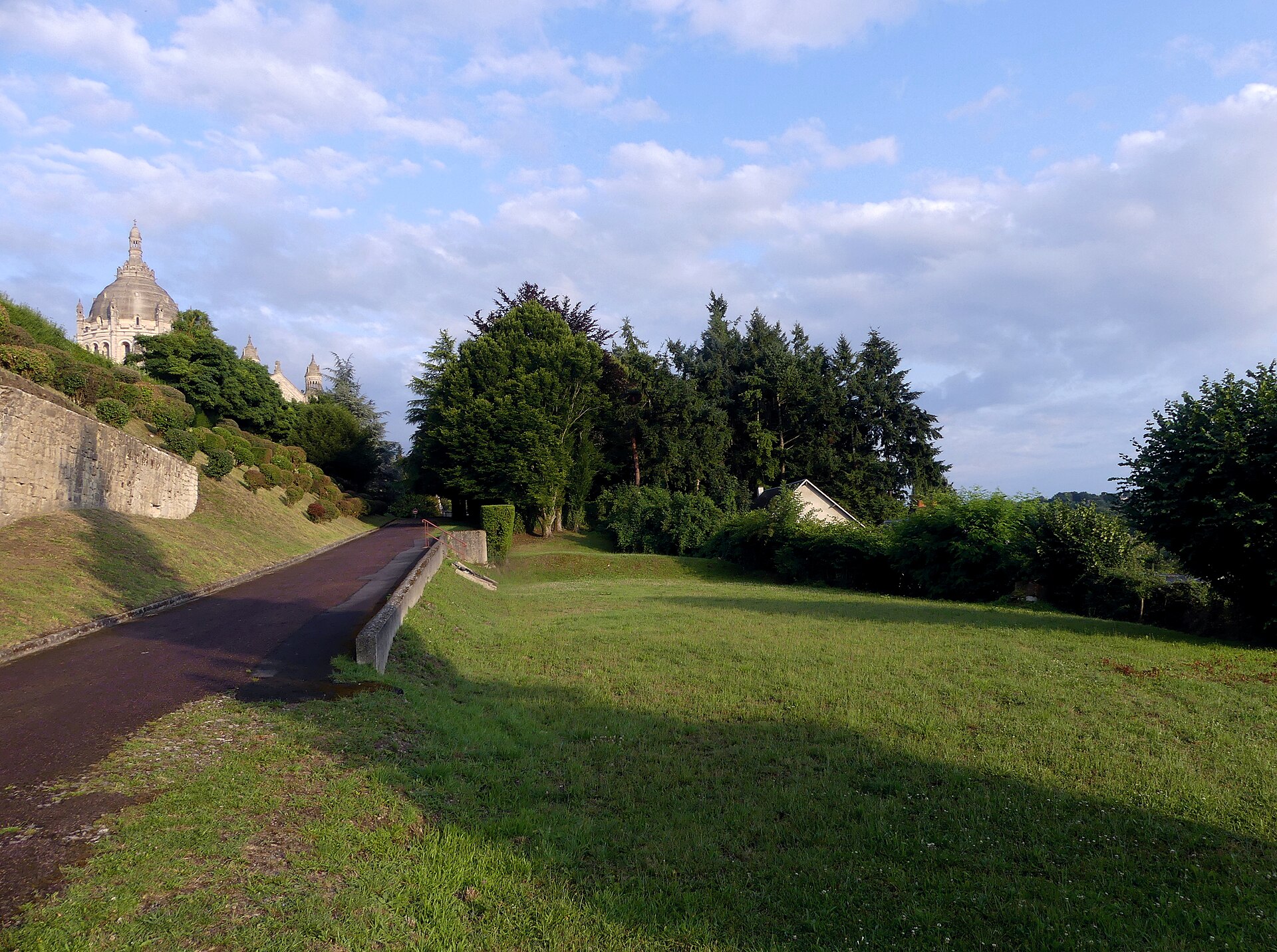 Une allée traverse le parc au pied de la basilique de Lisieux, en fin de journée