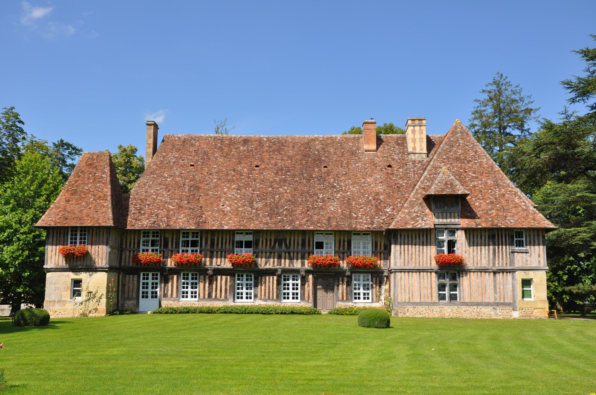 Le logis à pans de bois du manoir de Bellou, derrière sa pelouse